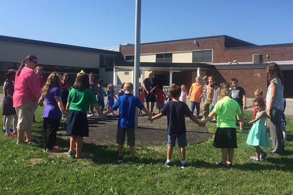 Students in a circle praying at flagpole.