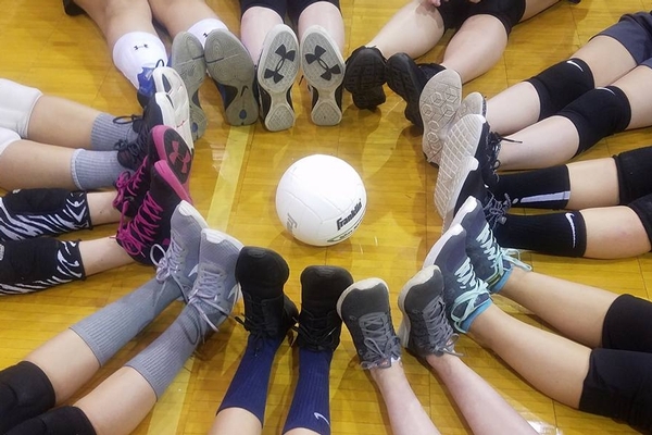 Volleyball team's feet making a circle around a ball